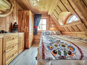 Dormitorio en cabaña de madera con cama y ventana en Jarogówka Stylowy dom góralski, en Obidowa