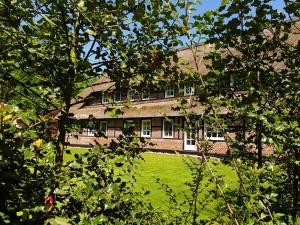 a large brick building with a green yard with trees at Hof Lindemann in Schneverdingen