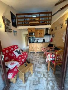 a living room with a red couch and a kitchen at LES FONTANILLES odeillo chalet 60 WIFI & PARKING gratuit exposé plein sud & plein pied , draps & serviettes de toilettes non inclus, sabanas y toallas no incluidos in Font-Romeu-Odeillo-Via