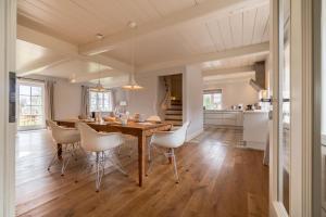 eine Küche und ein Esszimmer mit einem Holztisch und Stühlen in der Unterkunft Kapitänshaus West in Oldsum