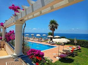 a swimming pool with umbrellas and chairs and the ocean at Hotel Albatros in Ischia