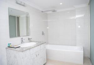 un bagno bianco con lavandino, vasca e specchio di Drishya Hotel a Kathmandu