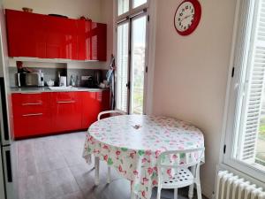 a kitchen with a table and red cabinets at Face à l'hôtel de ville grand et lumineux appartement in Angoulême