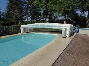 a large swimming pool with a pavilion next to it at Private Gite with heated pool with retractable cover and hot tub in Cendrieux