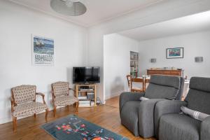 Una sala de estar con un sofá y sillas y un televisor. en Grande Brévinoise dans les pins, en Saint-Brevin-les-Pins