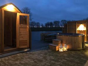 ein kleines Holzgebäude mit Whirlpool und Beleuchtung in der Unterkunft Ferienwohnungen Gut Oestergaard in Steinberg