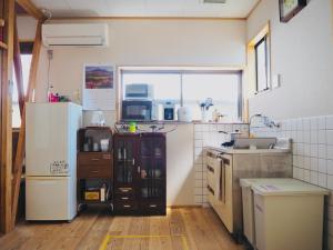 a kitchen with a refrigerator and a sink at Backpackers Hostel TSUBAMENOYADO in Shizuoka
