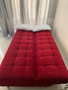 a red bed with two pillows on top of it at Garden View 1 BHK2BR Appt., Rio De Goa TATA Housing in Sancoale