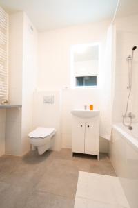 Baño blanco con aseo y lavamanos en Apartament Bravo, en Łódź