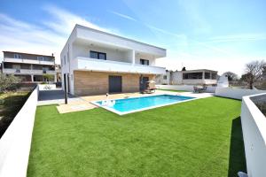 een grote achtertuin met een zwembad en gras bij Apartman Villa Marina in Vodice