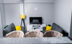 Kisii的住宿－Stay.Plus Oark Apartment Kisii，客厅配有桌椅和电视。