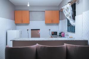 Kisii的住宿－Stay.Plus Oark Apartment Kisii，厨房配有柜台和一些棕色椅子