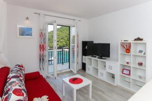 a living room with a red couch and a tv at Apartments Posta in Saplunara