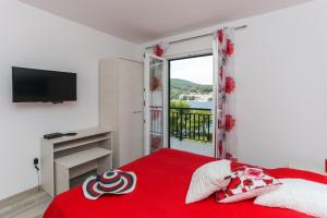 a bedroom with a red bed with a red blanket at Apartments Posta in Saplunara
