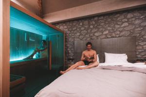Tsikeli Boutique Hotel Meteora - Adults Friendly في كالامباكا: رجل يجلس على سرير في غرفة
