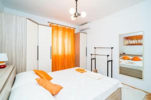 a bedroom with a large white bed with orange pillows at Rooms Rita in Dubrovnik