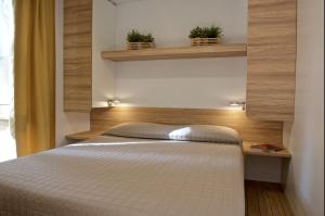 a bedroom with a bed and two plants on shelves at Le Dune Villaggio in Lido Di Fondi