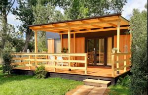 a wooden cabin with a deck in the grass at Le Dune Villaggio in Lido Di Fondi