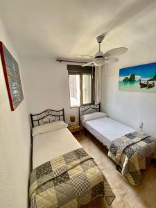 1 dormitorio con 2 camas y ventilador de techo en La Felicidad VYBDénia, en Denia