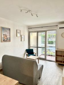 uma sala de estar com um sofá e uma cadeira em Chaleureux Studio - Calme et Lumineux - Point Zéro - Proximité Plage et Centre Ville em La Grande-Motte