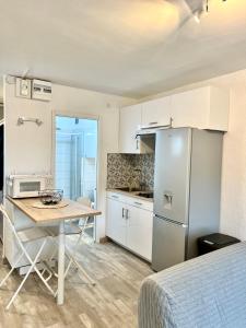 uma pequena cozinha com uma mesa e um frigorífico em Chaleureux Studio - Calme et Lumineux - Point Zéro - Proximité Plage et Centre Ville em La Grande-Motte