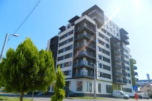 a tall apartment building with a tree in front of it at Panorama Luxury Apartment in Oradea