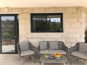 eine Terrasse mit 2 Stühlen und einem Tisch mit Obst darauf in der Unterkunft מבט אל הואדי in Abū Ghaush
