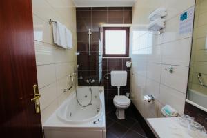 a bathroom with a tub and a toilet and a sink at Hotel Vila Tina in Trogir