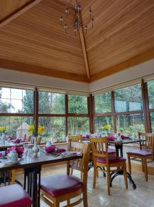a dining room with tables and chairs and windows at Glenn Eireann House in Cushendun