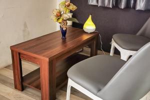 a wooden table with a vase of flowers and a chair at RedDoorz Plus @ Taman Madiun in Madiun
