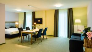 a hotel room with a table and chairs and a bed at Nutzwedel Resort Farmers Lodge in Horst in Holstein