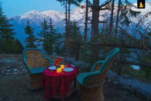 a table and two chairs with a table and a mountain at The Monk Campsite by Livingstone in Kalpa