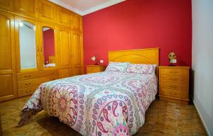 1 dormitorio con cama y pared roja en Solarium Agaete Valley Retreat 3-BR, en Agaete