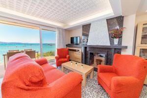 a living room with orange chairs and a fireplace at Seafront Apartment Voramar 31 by Sealand Villas in Port de Pollensa