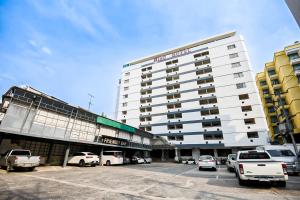 a large white building with cars parked in a parking lot at Pattaya Hiso Hotel in Pattaya South