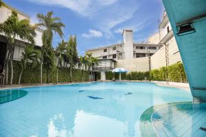 a large blue swimming pool with palm trees and a building at Pattaya Hiso Hotel in Pattaya South