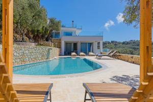 a swimming pool with two chairs and a house at Villa Prokimea by PosarelliVillas in Makrádes