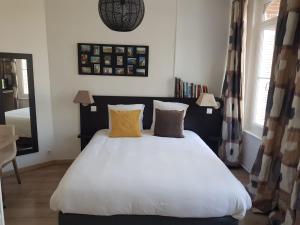 a bedroom with a large white bed with two yellow pillows at Le Clos des Lodges in Bernay
