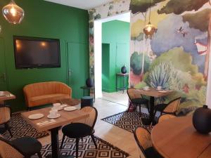 a restaurant with tables and chairs and a green wall at Le Clos des Lodges in Bernay