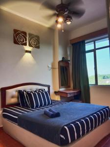 a bedroom with a bed with a ceiling fan at GloRy BeAch ResOrt private apartment in Port Dickson
