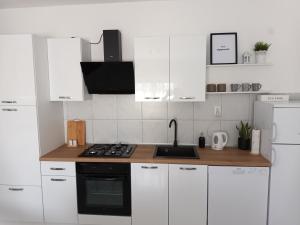 - une cuisine blanche avec évier et cuisinière dans l'établissement Holiday house Ana, à Skradin