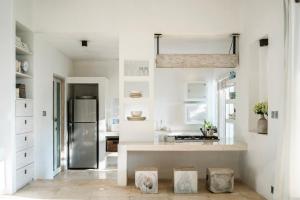 a kitchen with white walls and a stainless steel refrigerator at Crescent Moon in Ubud