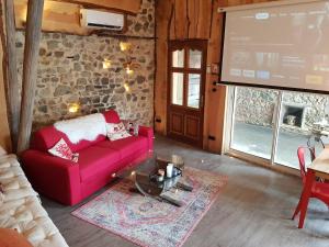 a living room with a red couch and a screen at Ancien cuvage du Beaujolais - Studio tout confort - BY PRIMO C0NCIERGERIE in Saint-Didier-sur-Beaujeu