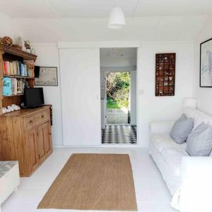 een witte woonkamer met een bank en een tafel bij Sea Forever - Beautiful Chalet which Overlooks the Sea! Amazing Views,Lovely Interior and Set Within the Best Part of Lyme with Beaches, Restaurants and Harbour all on your Doorstep! Rated Highly in Lyme Regis