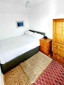 a bedroom with a bed and a wooden dresser at Sea Forever - Beautiful Chalet which Overlooks the Sea! Amazing Views,Lovely Interior and Set Within the Best Part of Lyme with Beaches, Restaurants and Harbour all on your Doorstep! Rated Highly in Lyme Regis