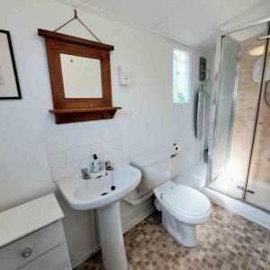 a white bathroom with a toilet and a sink at Sea Forever - Beautiful Chalet which Overlooks the Sea! Amazing Views,Lovely Interior and Set Within the Best Part of Lyme with Beaches, Restaurants and Harbour all on your Doorstep! Rated Highly in Lyme Regis