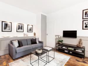 a living room with a couch and a tv at LivinParis - Luxury 2 Bedrooms Grands-Boulevards I in Paris