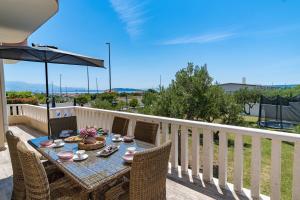 a table with chairs and an umbrella on a balcony at Villa Suker - Jacuzzi, Pool, Sauna in Kaštela