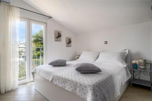a white bedroom with a bed with pillows on it at Villa Suker - Jacuzzi, Pool, Sauna in Kaštela +41 photos
