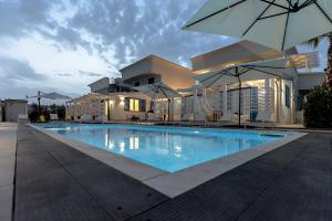 una piscina con sombrilla frente a un edificio en La Scala Suite en Realmonte